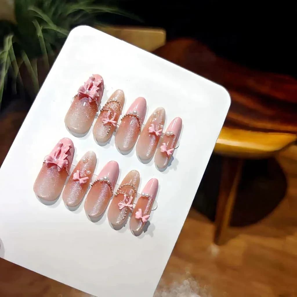 Mākslīgie nagi rozā mežģīņu loka un kaķa acu efektā, gari stiletto