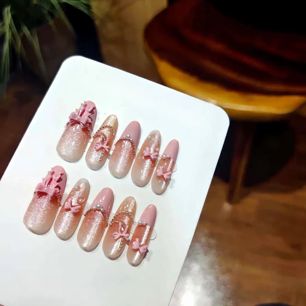 Mākslīgie nagi rozā mežģīņu loka un kaķa acu efektā, gari stiletto